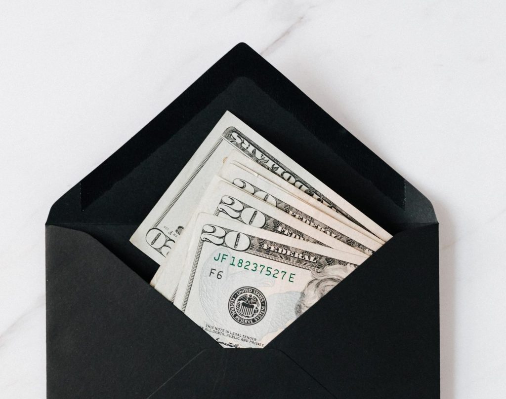 (alt-text: Paper bills are tucked into a black envelope to help someone reduce their spending for a minimalist lifestyle challenge.) 